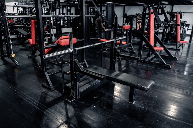 Olympic bench press with red-padded machines behind at Strength Factory