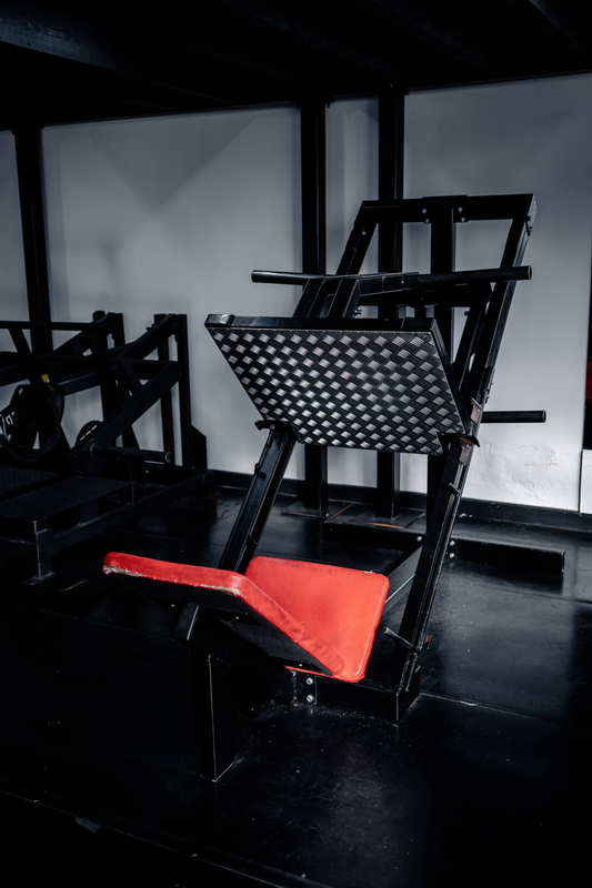 Plate-loaded leg press with red seat pad at Strength Factory gym